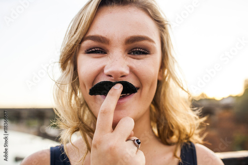 Caucasian teenage girl playing with fake mustache photo