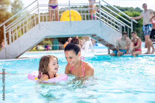 Mother and daughter in swimming pool, aquapark. Sunny summer.