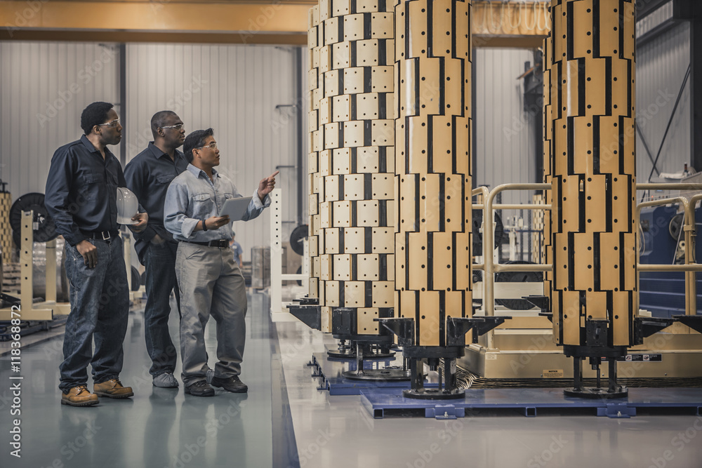 Workers looking at equipment in factory Workers looking at equipment in factory