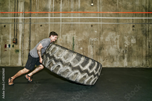 Caucasian man lifting large tire in gym