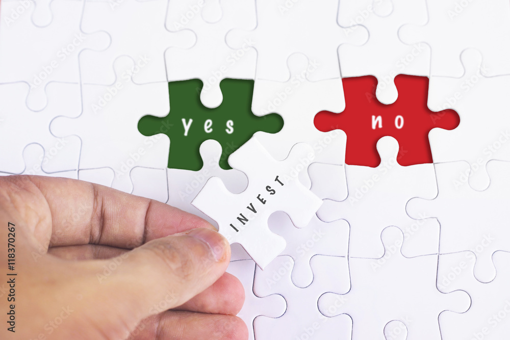 Business Concept - Female hand and missing puzzle with INVEST, YES NO WORD Business Concept - Female hand and missing puzzle with INVEST, YES NO WORD