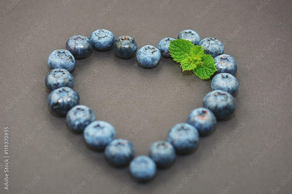 On a dark background lined with blueberries in a heart shape. On a dark background lined with blueberries in a heart shape.