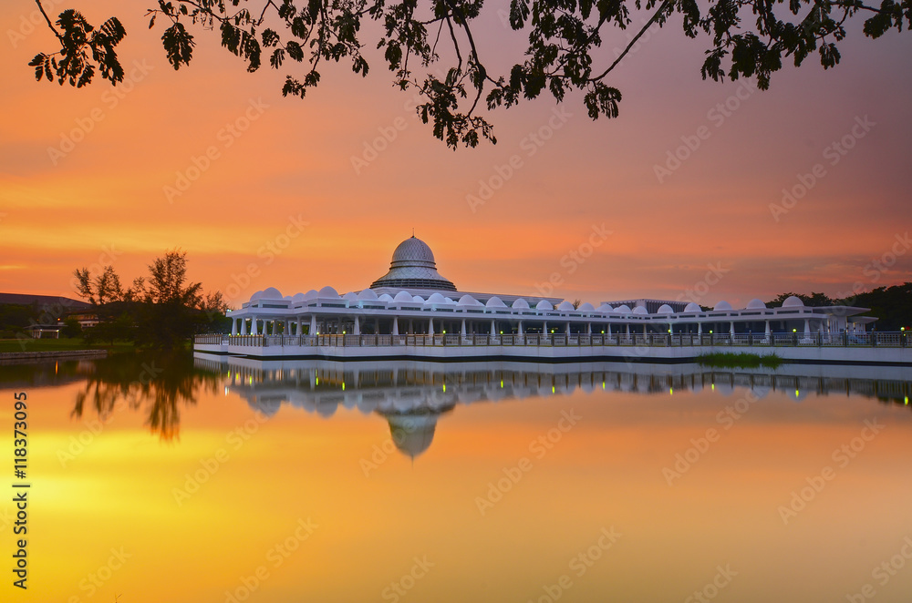 Obraz premium Beautiful white mosque during burning sunrise with mirror reflection on the lake