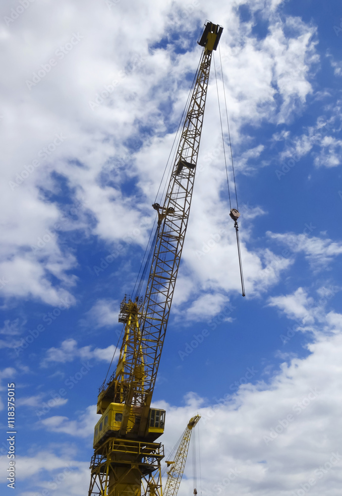 A Towering Yellow Crane Against a Blue and White Sky A Towering Yellow Crane Against a Blue and White Sky