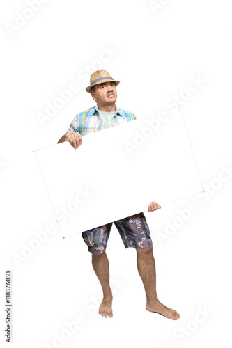     Мужчина в шортах в шляпе, босой держит в руках белый плакат на белом фоне.    