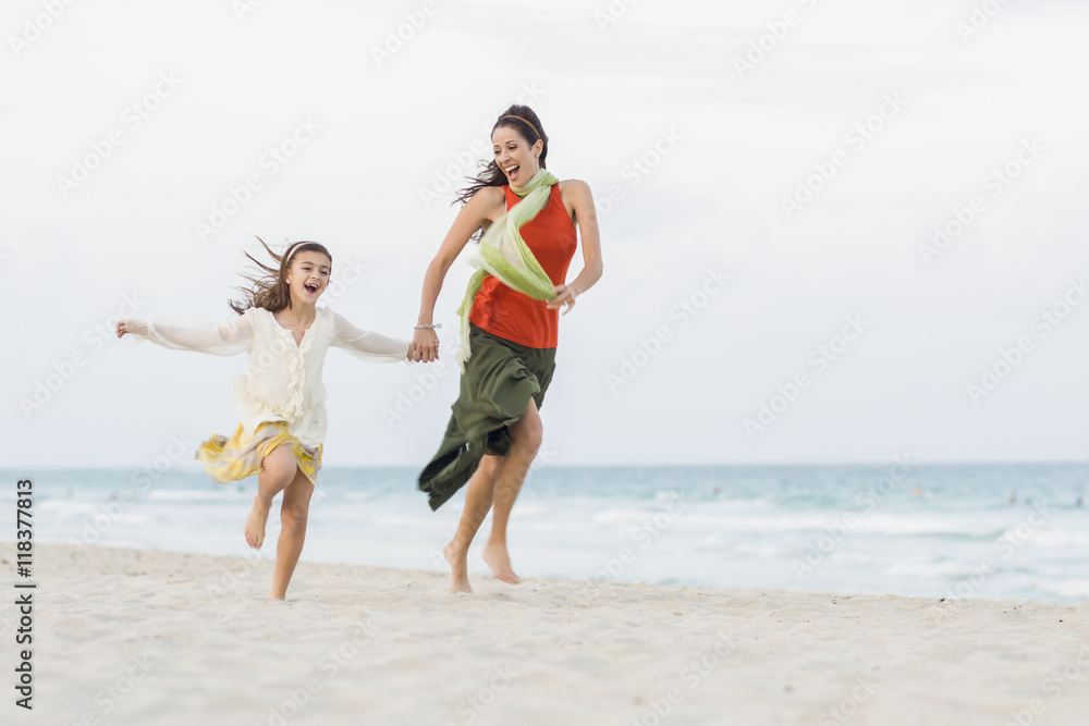 Hispanic mother and daughter running on beach Hispanic mother and daughter running on beach