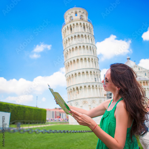 Young happy girl with toristic map on travel to Pisa. Tourist traveling visiting The Leaning Tower of Pisa.