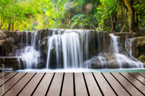 Wood table top on blurred waterfall tropical deep forest photo