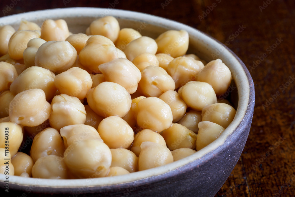Detail of cooked chickpeas in brown ceramic bowl on dark. Detail of cooked chickpeas in brown ceramic bowl on dark.