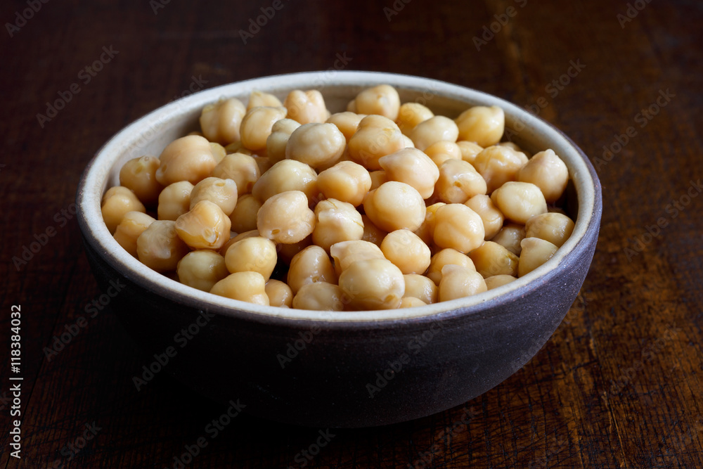 Cooked chickpeas in brown ceramic bowl isolated on dark. Cooked chickpeas in brown ceramic bowl isolated on dark.