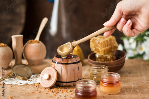 Honey background. Natural honey comb, glass jarand wooden bowls. On wooden rustic table. Soft focus