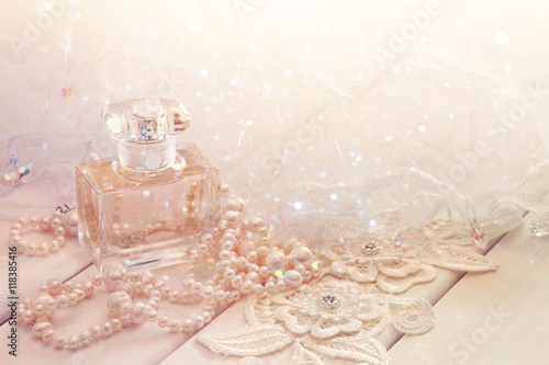 Dreamy photo of white pearls necklace and perfume bottle