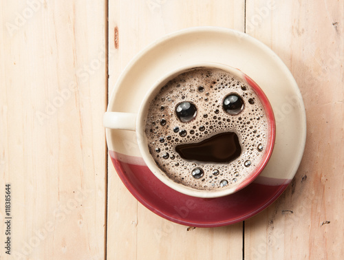Espresso Cup with smiley face on wooden table, vintege tone photo