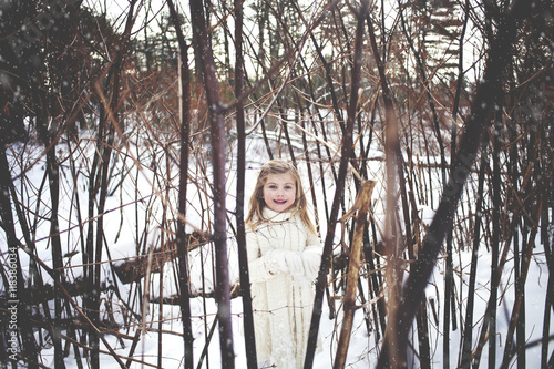 Caucasian girl playing in snowy forest photo