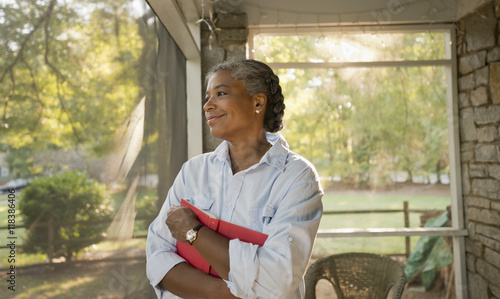Mixed race woman holding book on porch photo
