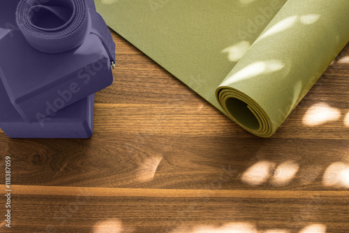 Yoga mat on wooden floor in evening light with shadows from window