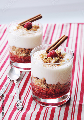 Homemade layered dessert or parfait with granola, raspberry jam and creamy yogurt in a glass. Healthy food and diet concept. Selective focus.