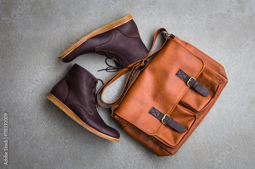 Men's casual outfits with brown boots and brown handbag on gray grunge background