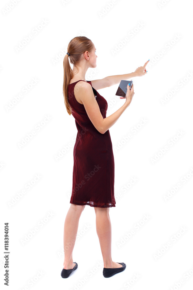 back view of pointing young beautiful girl with tablet computer. girl watching. Rear view people collection. backside view of person. Isolated over white background. Slim blonde in a burgundy back view of pointing young beautiful girl with tablet computer. girl watching. Rear view people collection. backside view of person. Isolated over white background. Slim blonde in a burgundy