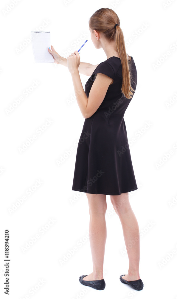 back view of stands woman takes notes in a notebook. girl watching. Rear view people collection. backside view of person. Isolated over white background. Blonde in a short black dress assures back view of stands woman takes notes in a notebook. girl watching. Rear view people collection. backside view of person. Isolated over white background. Blonde in a short black dress assures