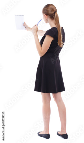 back view of  stands woman takes notes in a notebook. girl  watching. Rear view people collection.  backside view of person.  Isolated over white background. Blonde in a short black dress assures