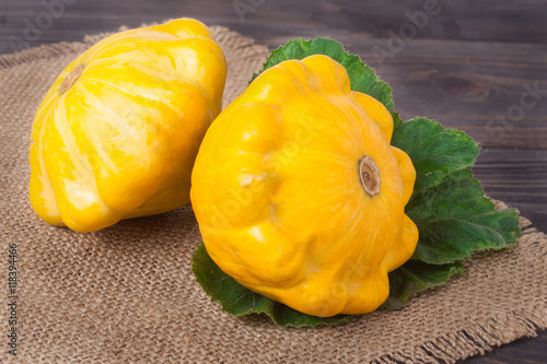 two yellow squash on a wooden background with napkin of burlap