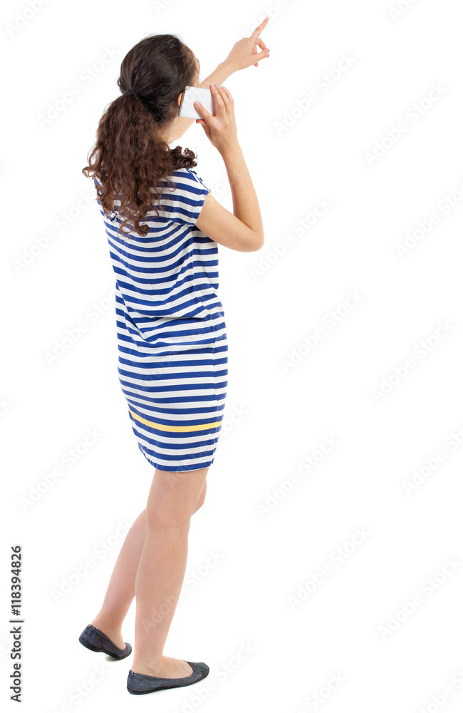 back view of standing young beautiful woman using a mobile phone. girl watching. Rear view people collection. backside view of person. Isolated over white background. Swarthy girl in a checkered back view of standing young beautiful woman using a mobile phone. girl watching. Rear view people collection. backside view of person. Isolated over white background. Swarthy girl in a checkered
