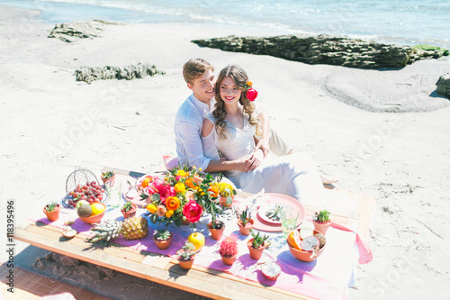 Newly married couple having breakfast at the seashore