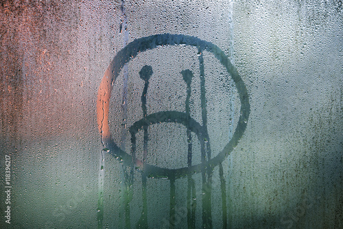 Valokuva Sad upside down smiley hand drawn symbol on wet glass background.
