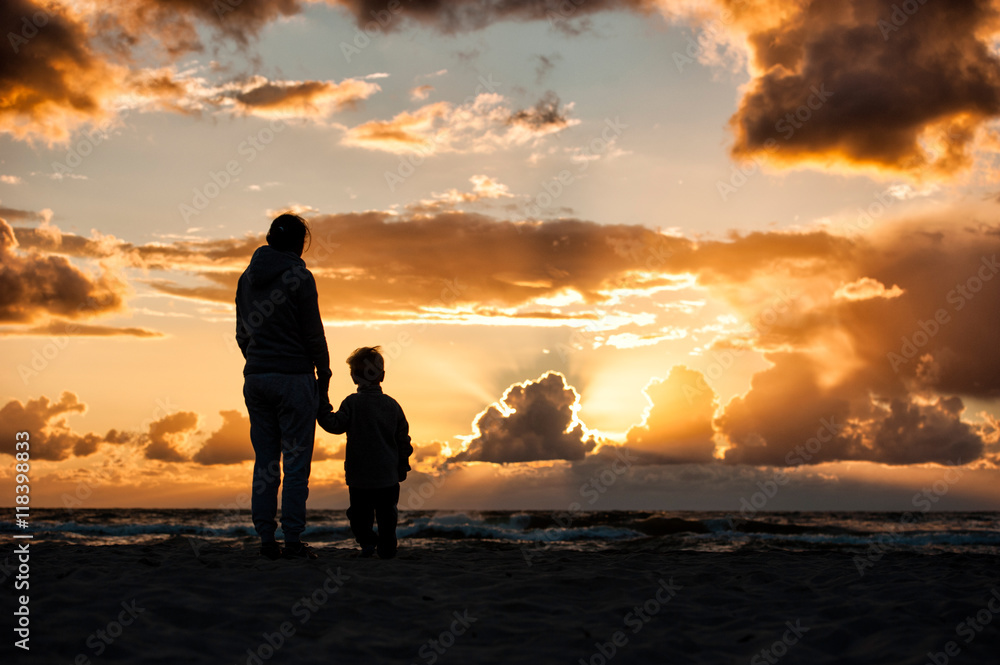 Fototapeta premium A woman holding a child's hand during sunset