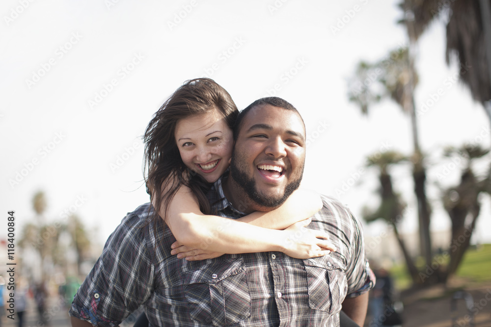 Grinning man giving wife piggyback ride Grinning man giving wife piggyback ride