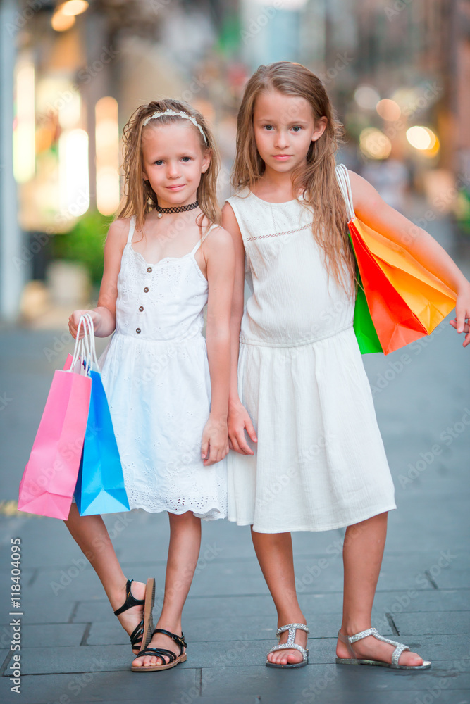 Adorable little girls on shopping. Portrait of kids with shopping bags in small italian town Adorable little girls on shopping. Portrait of kids with shopping bags in small italian town