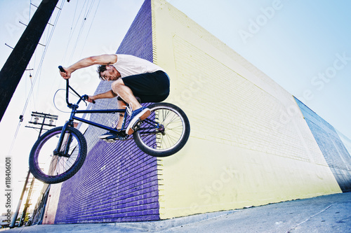 Caucasian man jumping on BMX bike on sidewalk photo