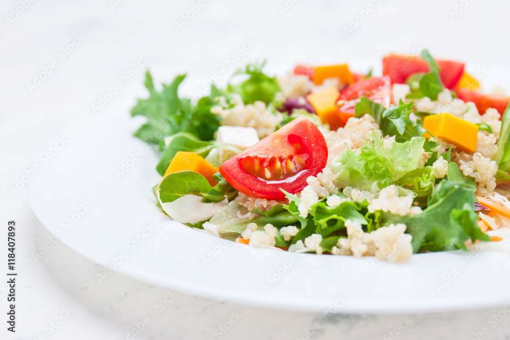 Homemade autumn healthy salad with quinoa, salad leaves, tomatoes, pumpkin and feta cheese on a white plate, closeup, selective focus Homemade autumn healthy salad with quinoa, salad leaves, tomatoes, pumpkin and feta cheese on a white plate, closeup, selective focus