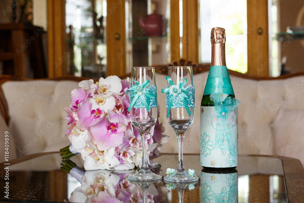 Wedding still life. Two decorated glasses, a bottle of champagne and bride's bouquet.