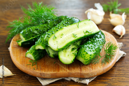 Freshly-salted cucumbers on a board with garlic and herbs