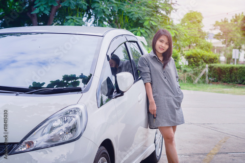 Portrait happy smiling young attractive woman standing next to new white car © Bankerd