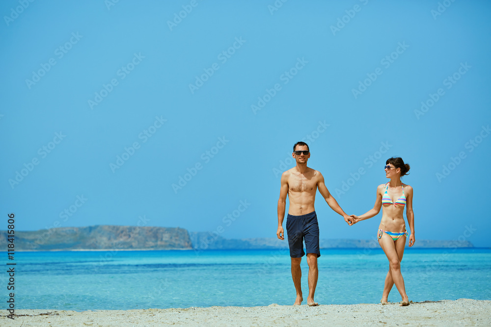 young happy couple walking on the beach at the sunset. Balos beach, Crete, Greece.
