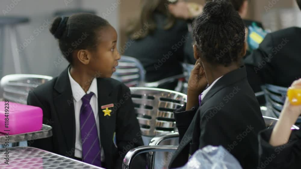 Happy young school children eating packed lunches in school cafeteria Happy young school children eating packed lunches in school cafeteria