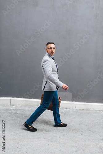 Shot of a stylish mature man crossing a city street and looking at the camera. On the way to meeting