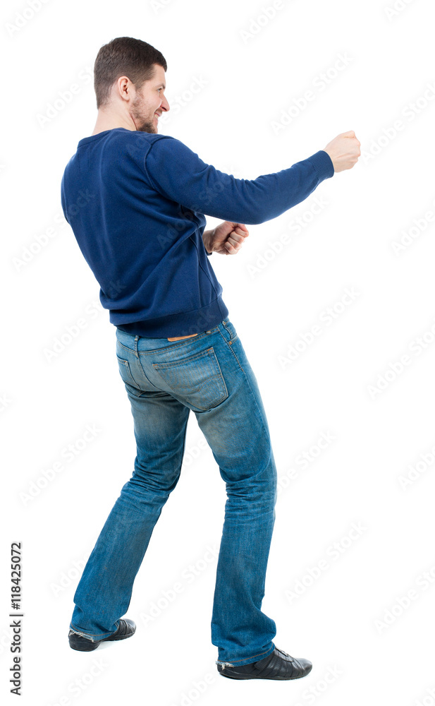 back view of standing man pulling a rope from the top or cling to something. Rear view people collection. backside view of person. Isolated over white background. bearded man in blue pullover pulls back view of standing man pulling a rope from the top or cling to something. Rear view people collection. backside view of person. Isolated over white background. bearded man in blue pullover pulls