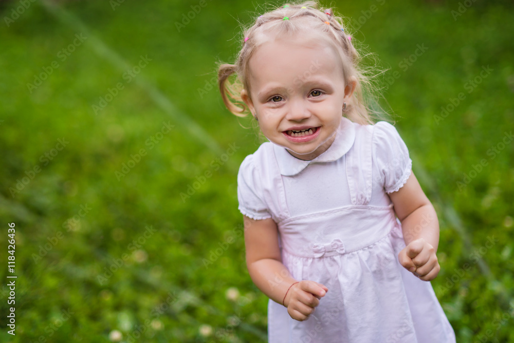 Little girl in white dress plays with sprinkler in the garden Little girl in white dress plays with sprinkler in the garden