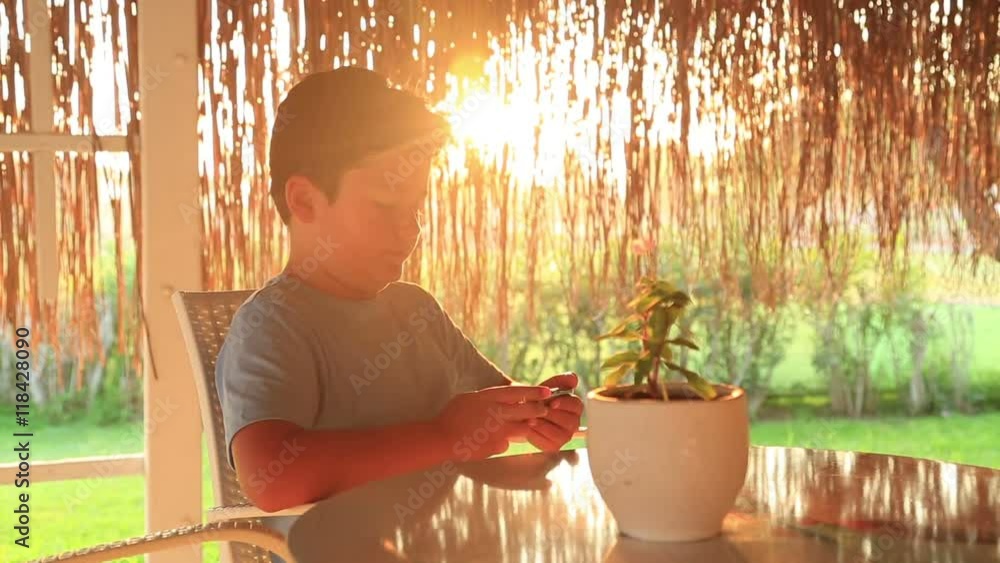 Little boy gaming on mobil phone at the cafe. Smartphone addiction
