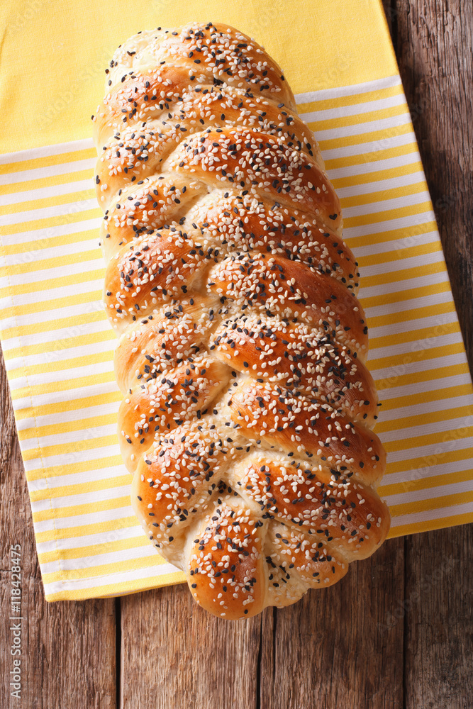 Freshly baked loaf of braided, with sesame seeds close up. Vertical top view
