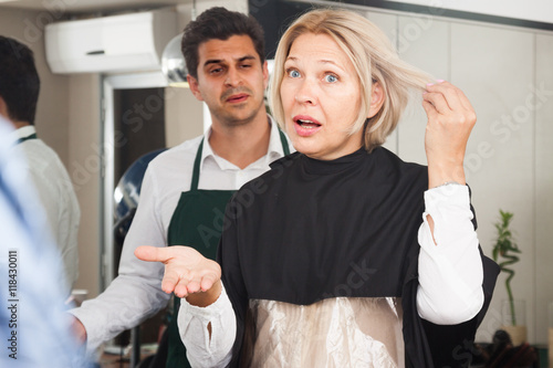 Furious mature woman screaming on hairdresser as hair cut badly