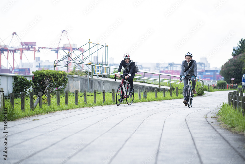 Two businessmen are riding on the road bike wearing a helmet