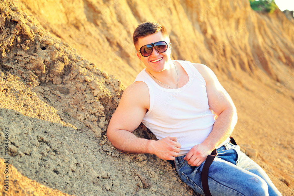 Portrait of a young attractive man laying down on white sand while on vacations on the beach. Portrait of a young attractive man laying down on white sand while on vacations on the beach.