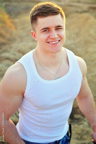 Portrait of a young attractive man laying down on white sand while on vacations on the beach.