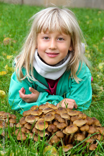 Portrait Mädchen hellblond liegt im Gras mit Pilzen photo