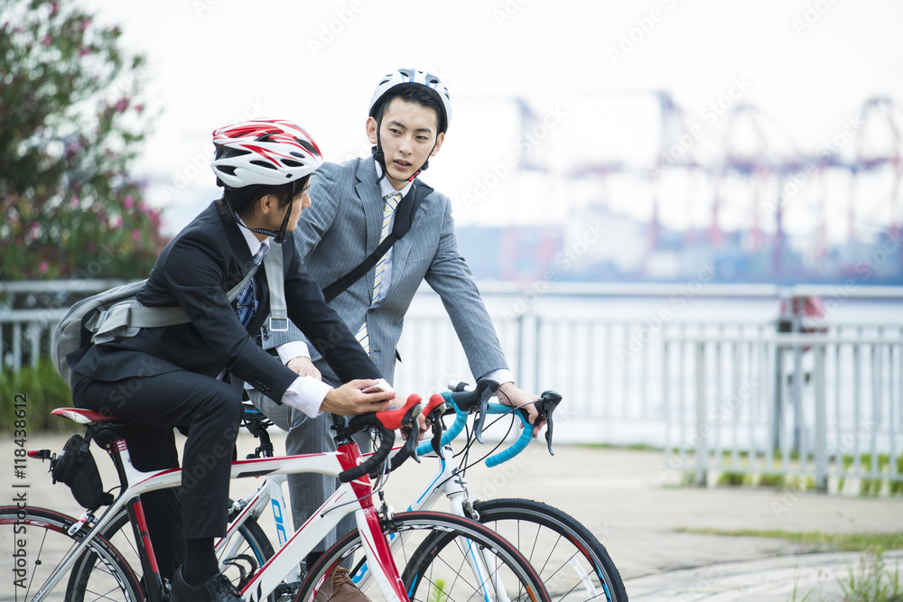 Obraz premium Two businessmen are talking while riding a bicycle